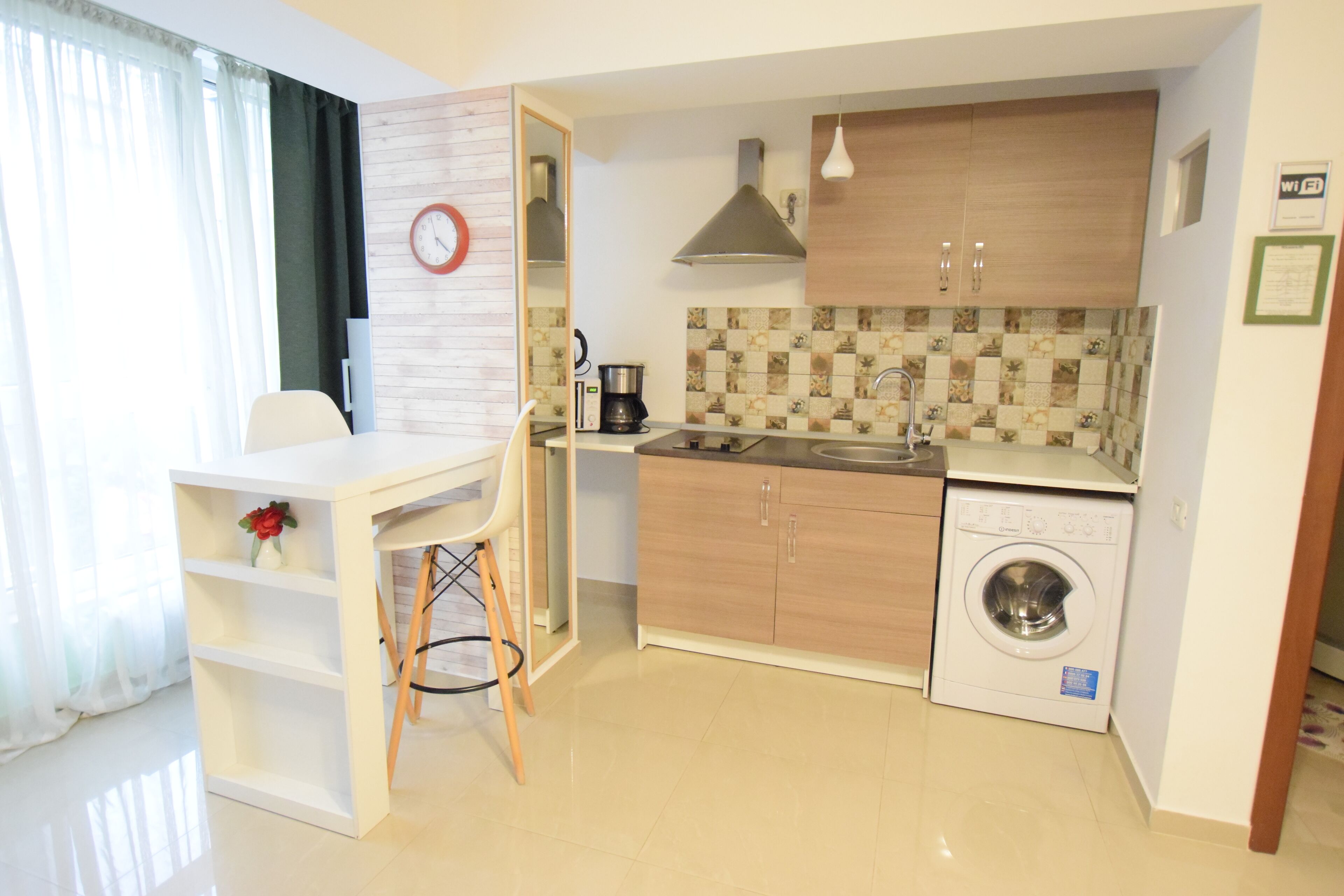 A compact kitchen with a sink, stove, and washing machine. There is a dining area with a table and chairs.