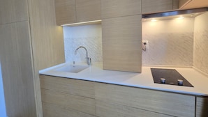 Une cuisine moderne dotée d’un évier encastré, de meubles de rangement en bois et d’une plaque de cuisson à induction noire.