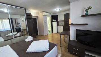 Een hotelkamer met een bed, een televisie, een bureau en een kitchenette.