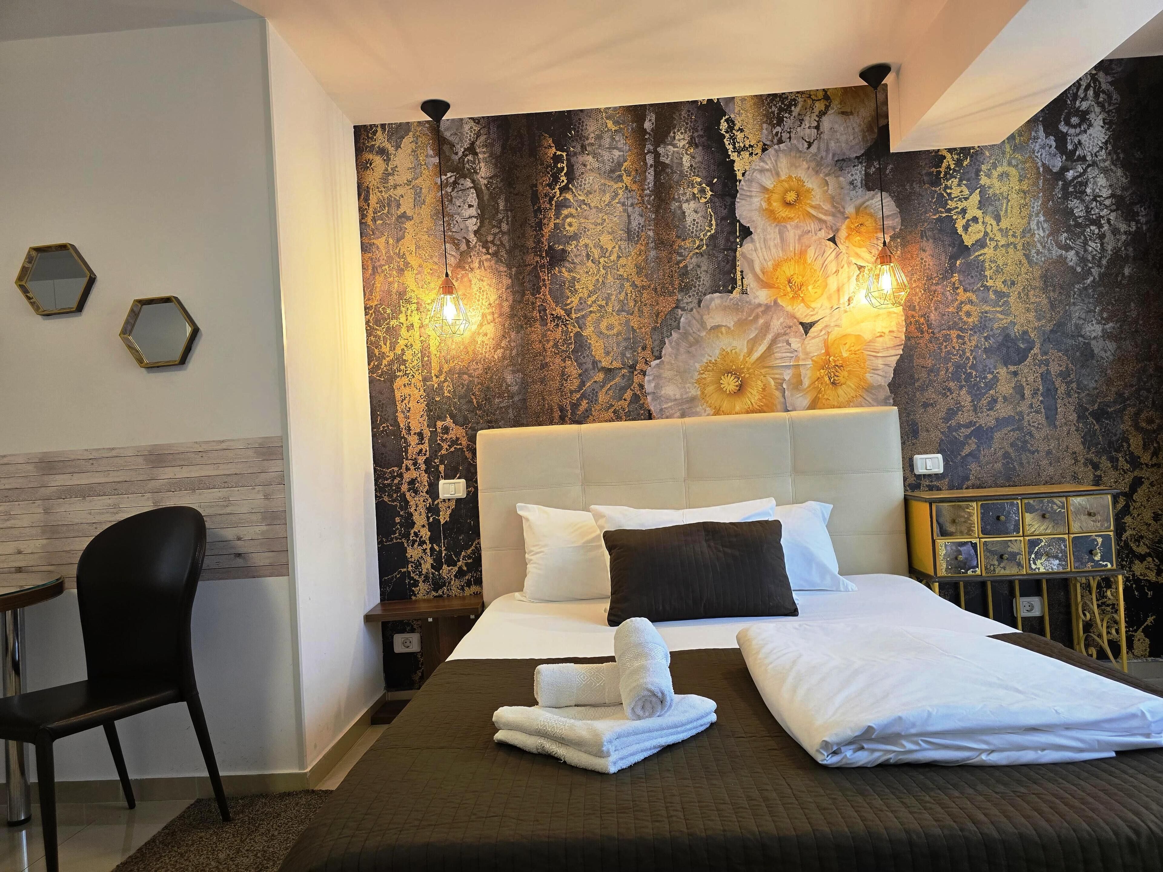 A bedroom with a large bed, a chair, a nightstand, and a decorative wall with flowers.