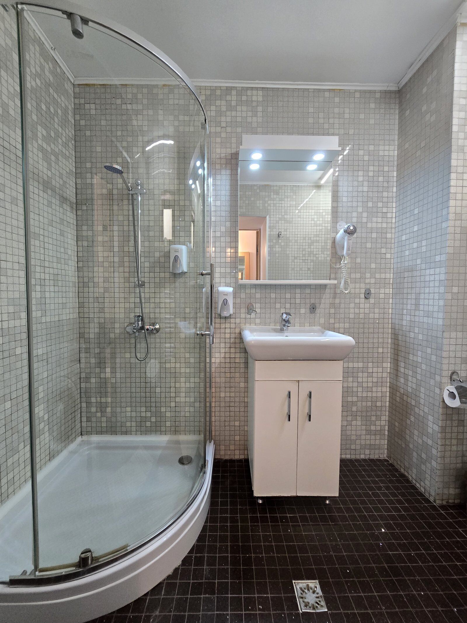 Une salle de bain avec une douche à parois de verre, un lavabo et un miroir.