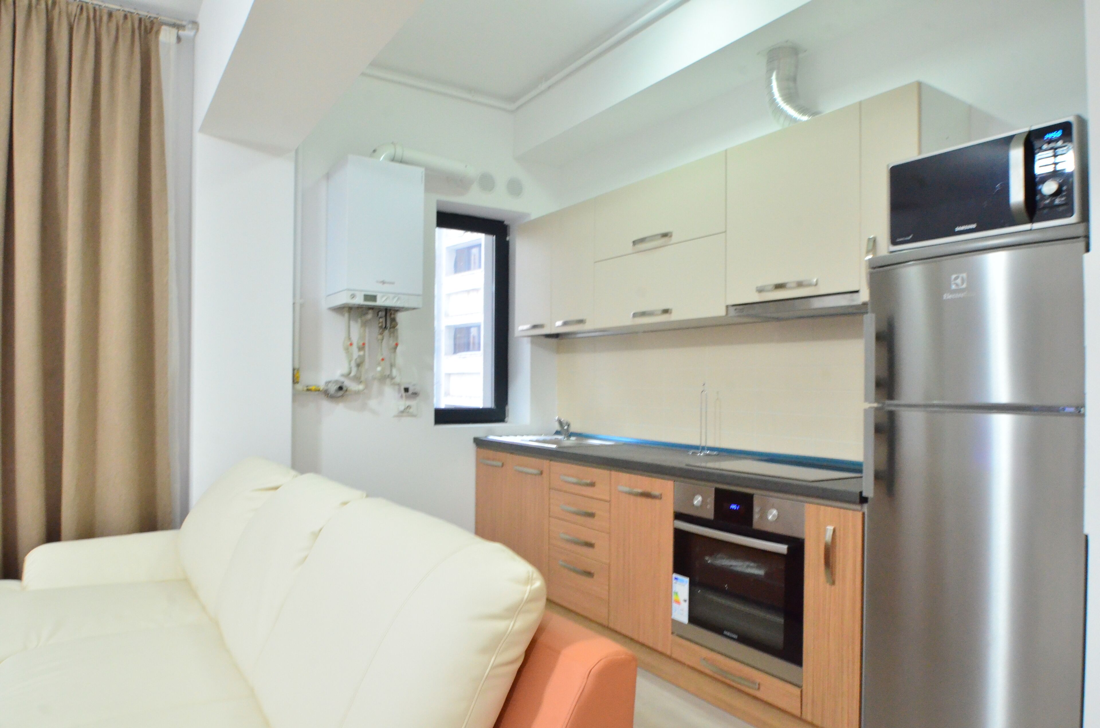 A compact kitchen with a refrigerator, oven, and a window.