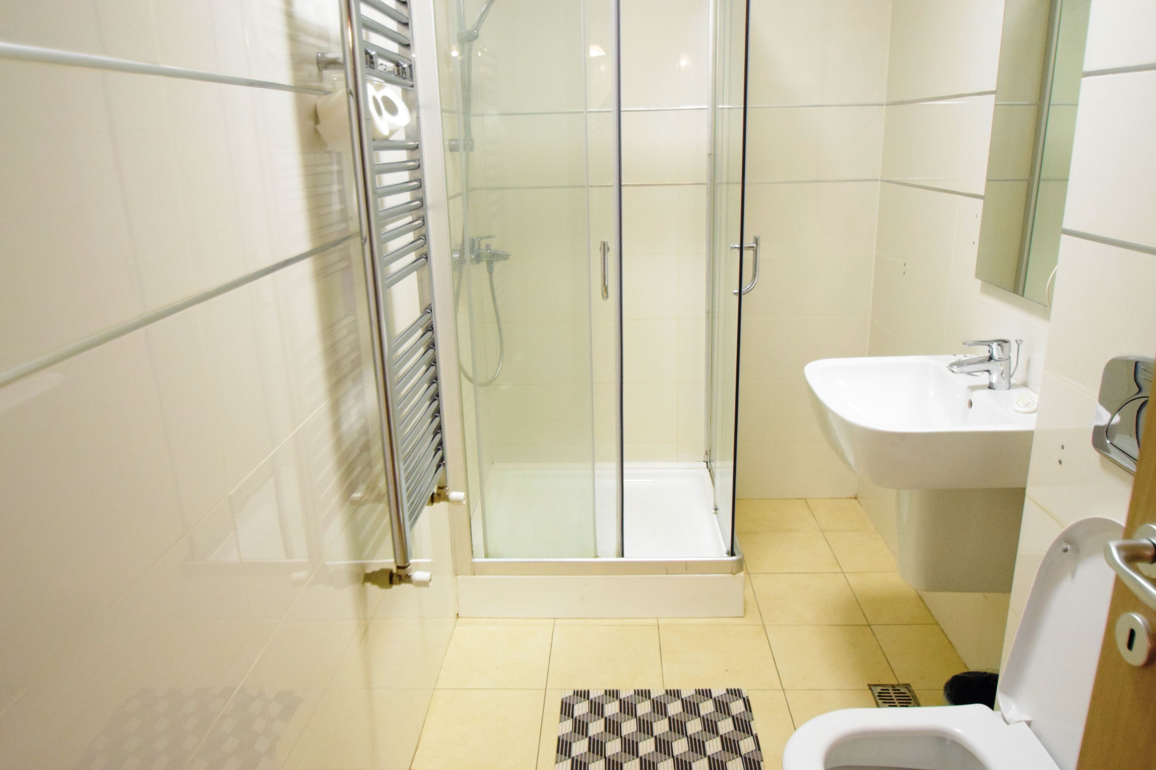Un baño con ducha de vidrio, lavamanos e inodoro.