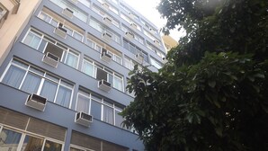Een meerlaags gebouw met veel airconditioners, een zichtbaar raam met gordijn en een lantaarnpaal.