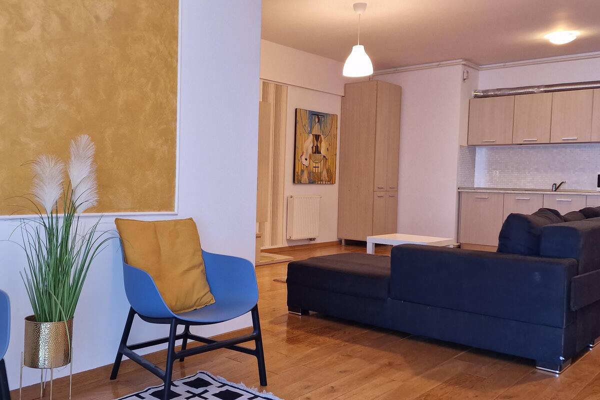 Una sala de estar moderna con un sofá, dos sillones, una mesita y una planta en maceta.