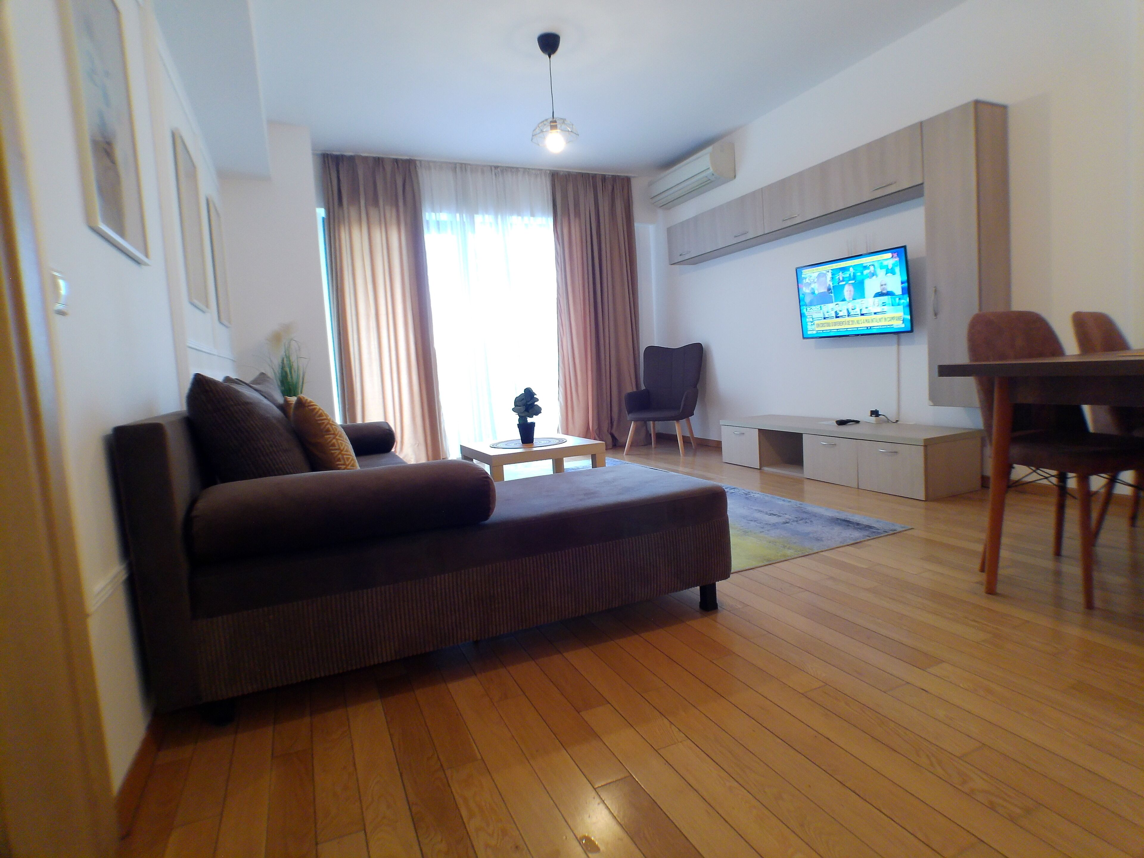 Un soggiorno moderno con un divano, un tavolino, una TV e un'area pranzo con sedie.