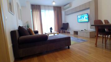 Un soggiorno moderno con un divano, un tavolino, una TV e un'area pranzo con sedie.