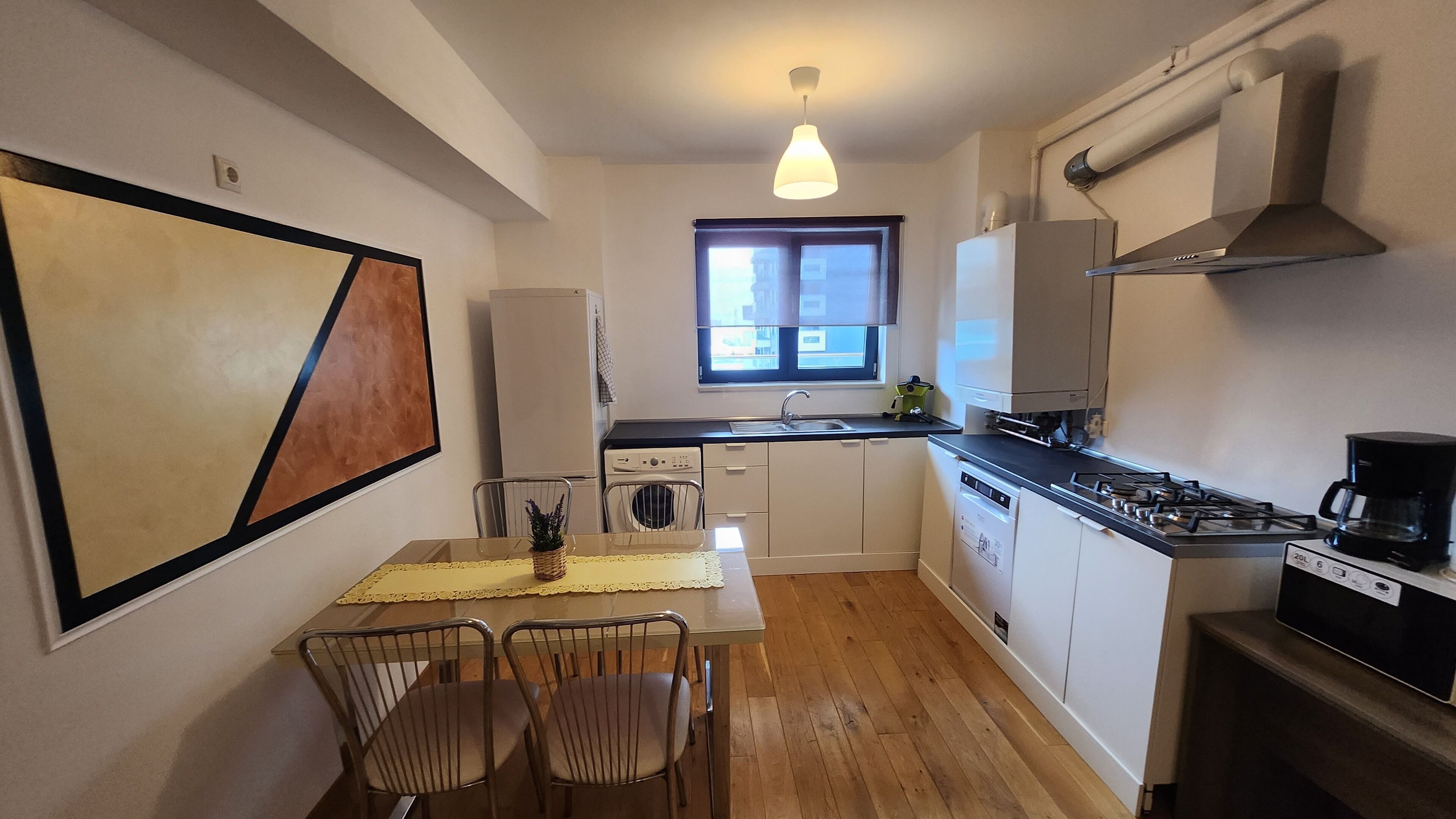 A compact kitchen with a dining area, a window, and a hanging light fixture.
