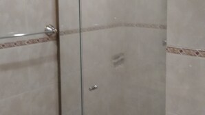A glass-enclosed shower area with a window, tiled walls, and a showerhead mounted on the wall. - Kitnet Hilário de Gouveia (Rio de Janeiro)