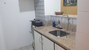 A kitchen with a sink, stove, and tiled backsplash. - Kitnet Hilário de Gouveia (Rio de Janeiro)