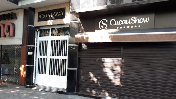 A storefront with a closed shutter, a sign reading "CacauShow," and a "Broadway" sign above the entrance. - Kitnet Hilário de Gouveia (Rio de Janeiro)