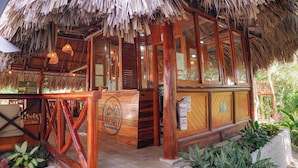 Une structure en bois avec un toit de chaume, des rampes en bois et une enseigne sur laquelle on peut lire « Yachay ».