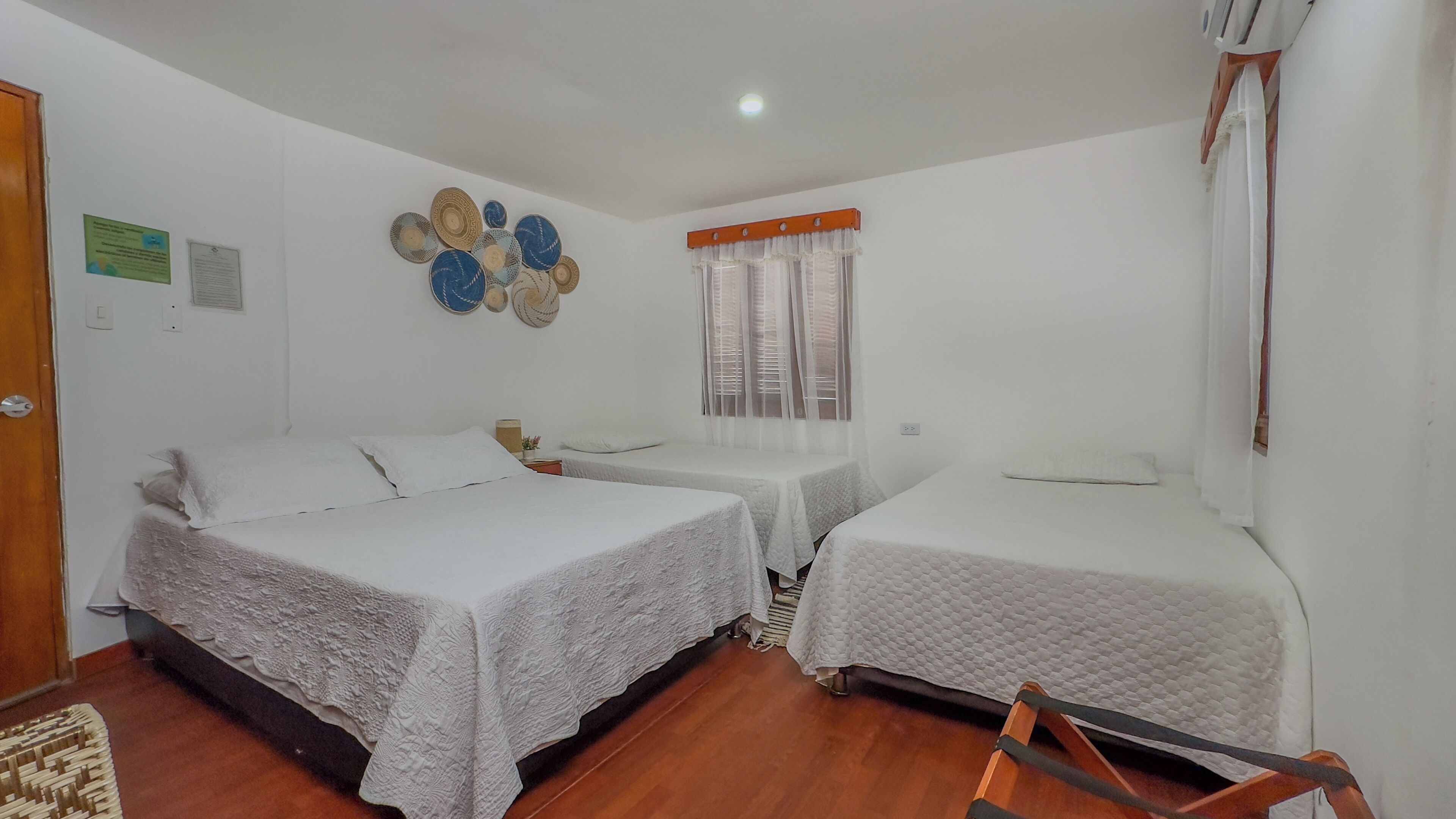 A room with two beds, a small table, and a window with curtains.