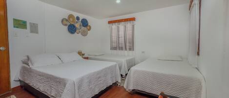 A room with two beds, a small table, and a window with curtains.