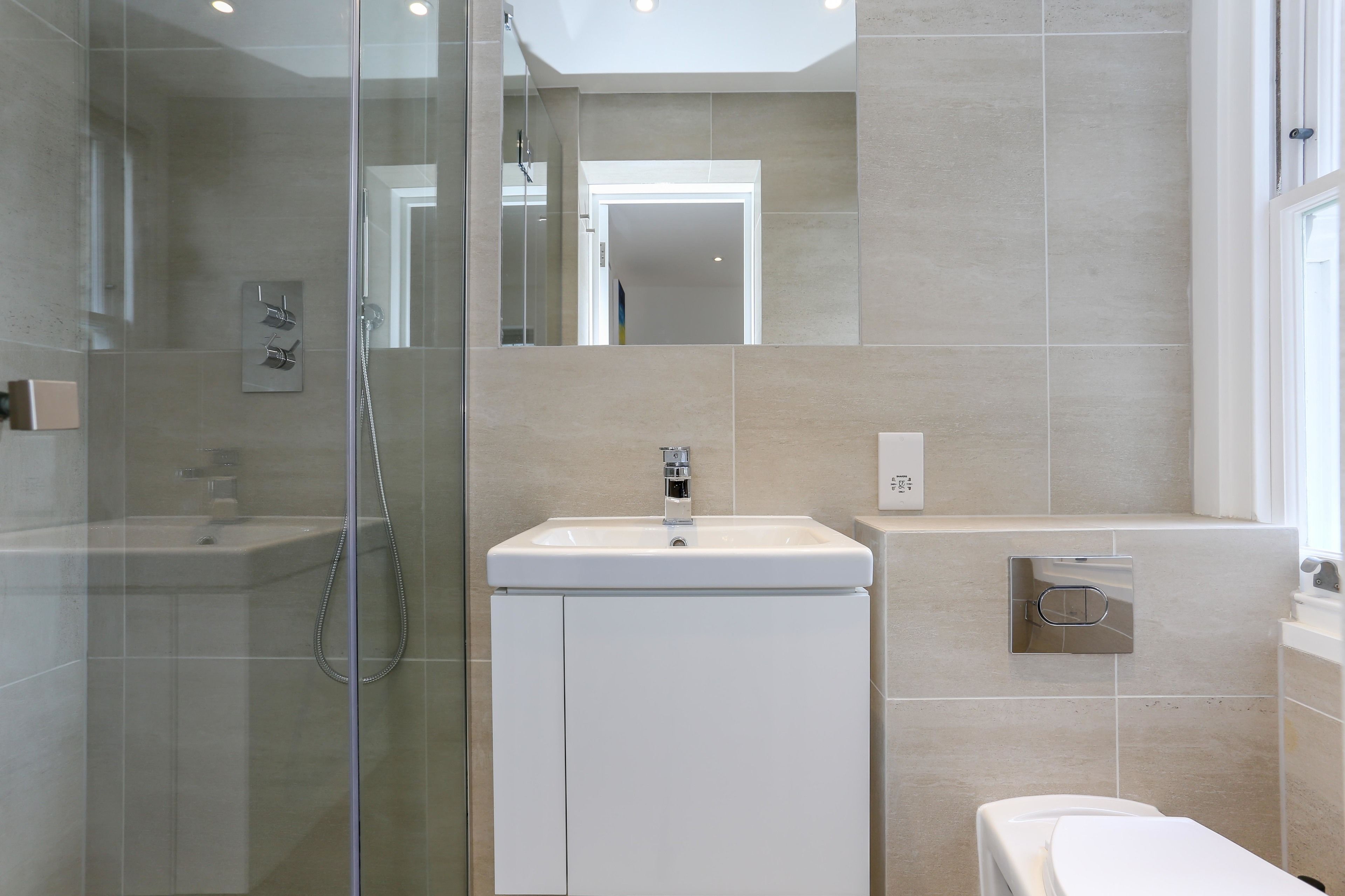 A modern bathroom with a glass-enclosed shower, a white sink, and a toilet.