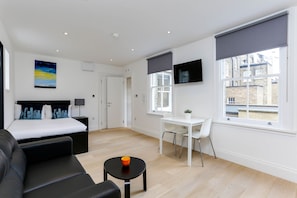 Relax in a serene bedroom with a large bed, a comfortable sofa, and a desk area.