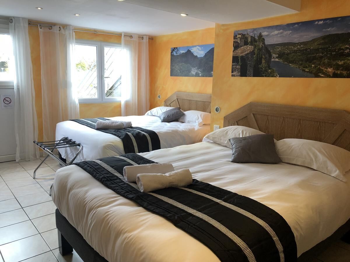 A hotel room with two beds, a window with curtains, a towel rack, and a painting on the wall.