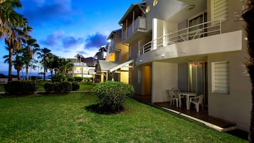 A modern hotel with a two-story structure, outdoor seating area, and a well-maintained lawn.