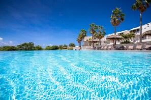 A clear blue pool with lounge chairs and palm trees, surrounded by a resort building. - Karibea Sainte Luce hotel (Sainte-Luce)