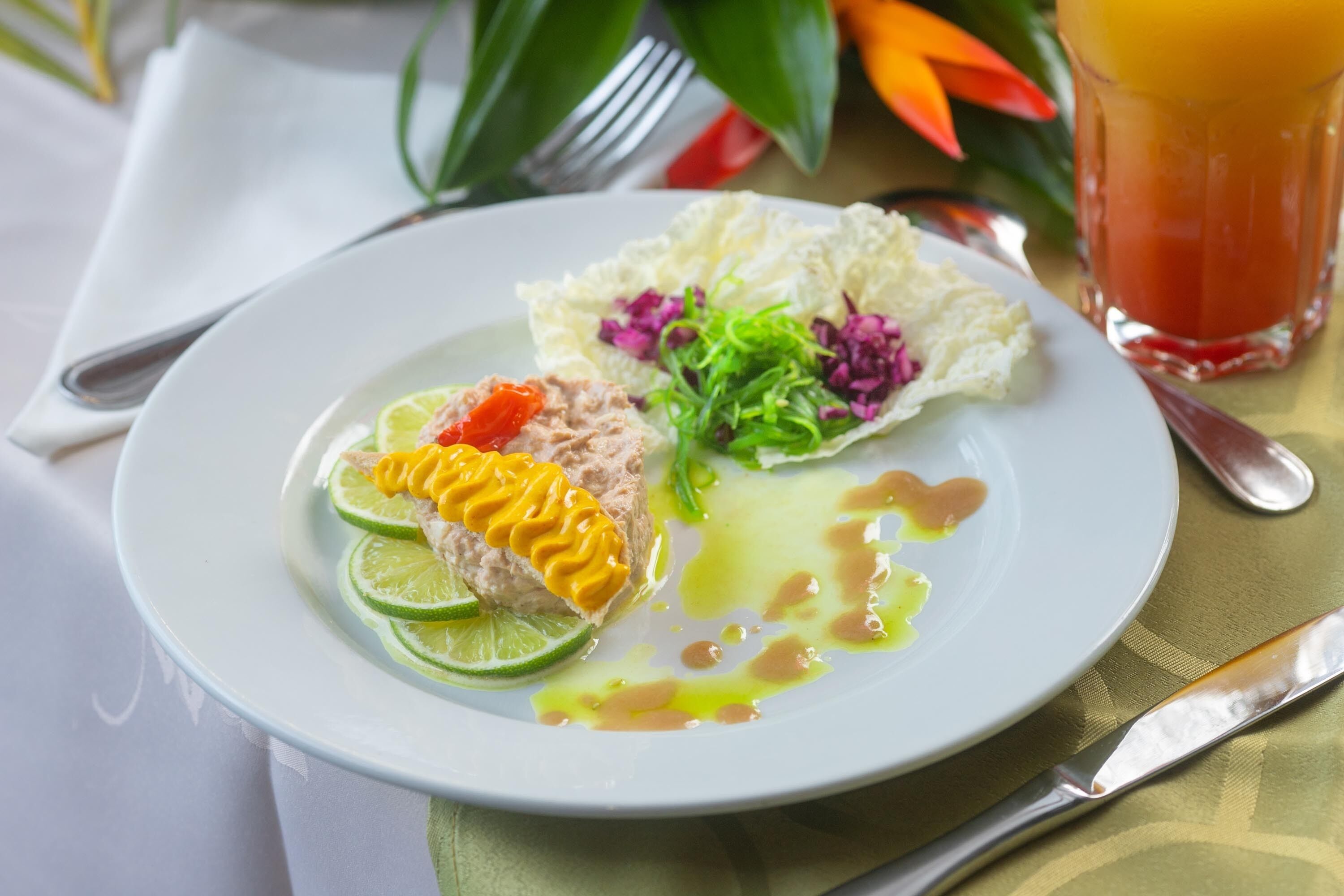Ein Teller mit Salat, einer Limettenscheibe und einem Getränk.