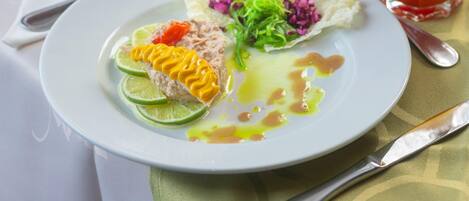 Ein Teller mit Salat, einer Limettenscheibe und einem Getränk.