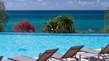 Relax by the ocean with a serene pool surrounded by lounge chairs.