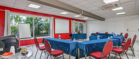 Una sala de conferencias con mesas, sillas, un proyector y una pantalla.