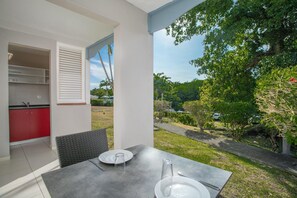 A modern kitchen with red cabinets and a dining area with a table and chairs. - Karibea Sainte Luce hotel (Sainte-Luce)