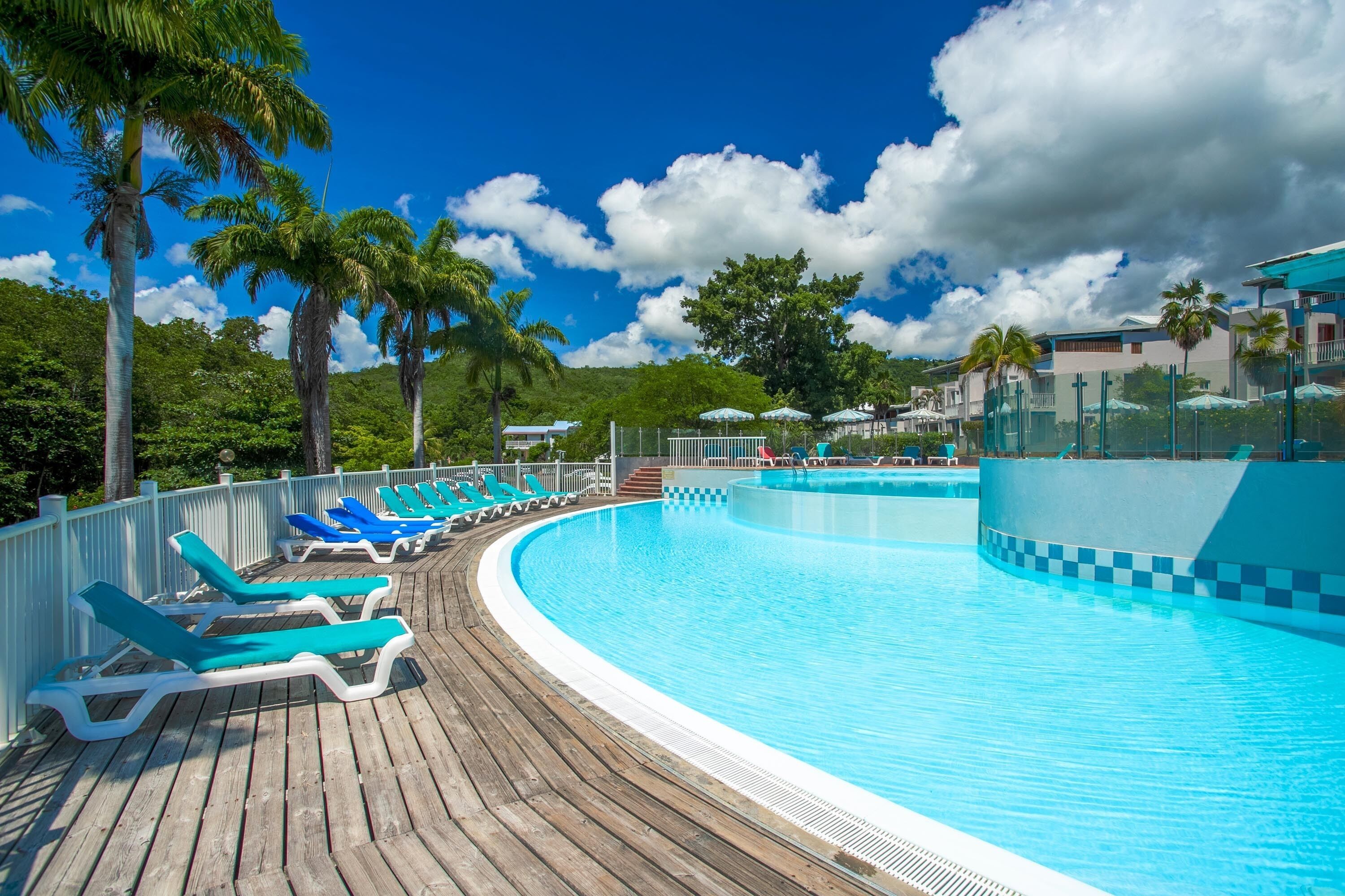 A pool area with blue lounge chairs and a wooden deck.