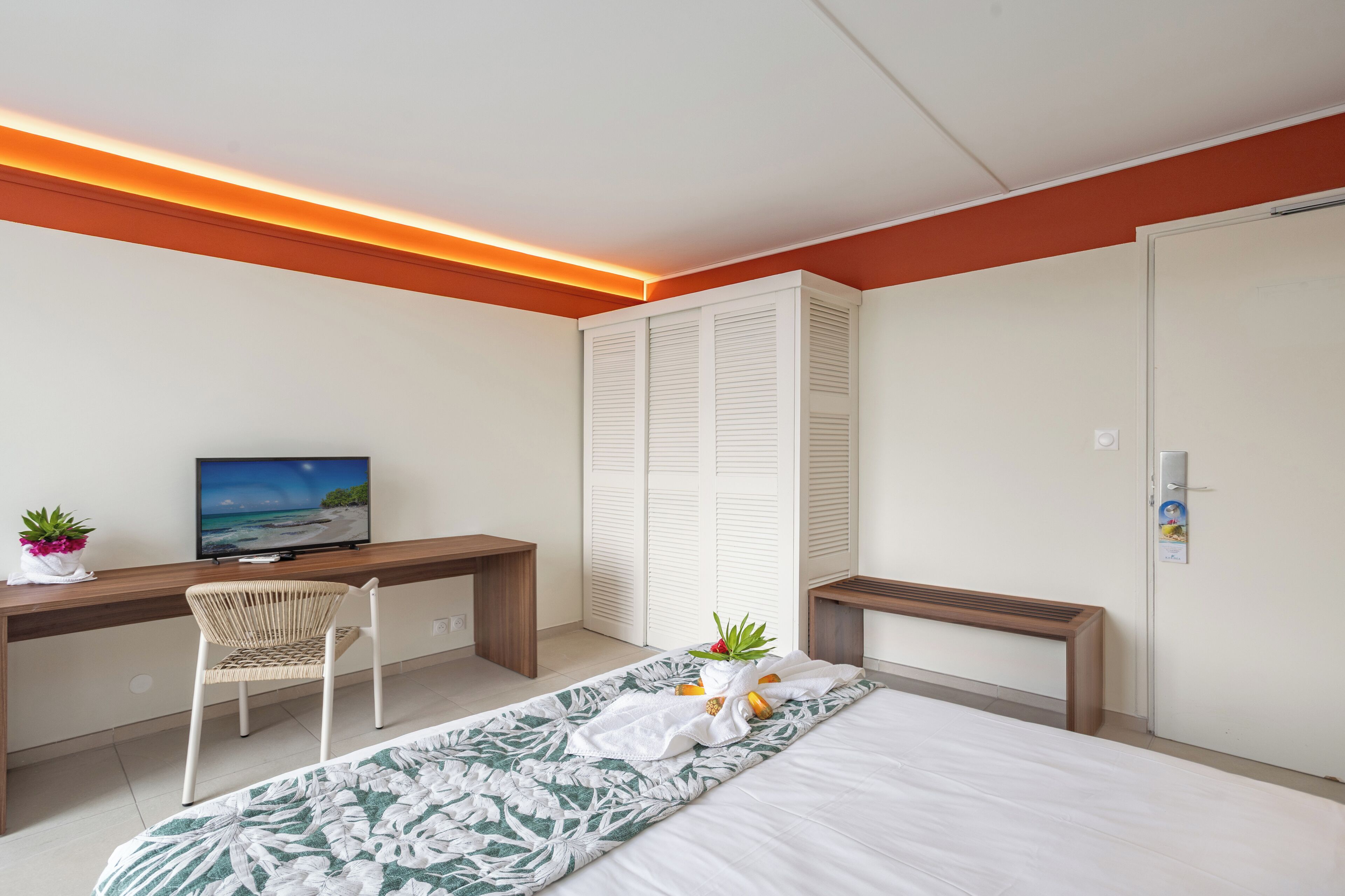 A modern bedroom with a bed, a desk, a chair, a television, and a wardrobe.
