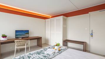 A modern bedroom with a bed, a desk, a chair, a television, and a wardrobe.