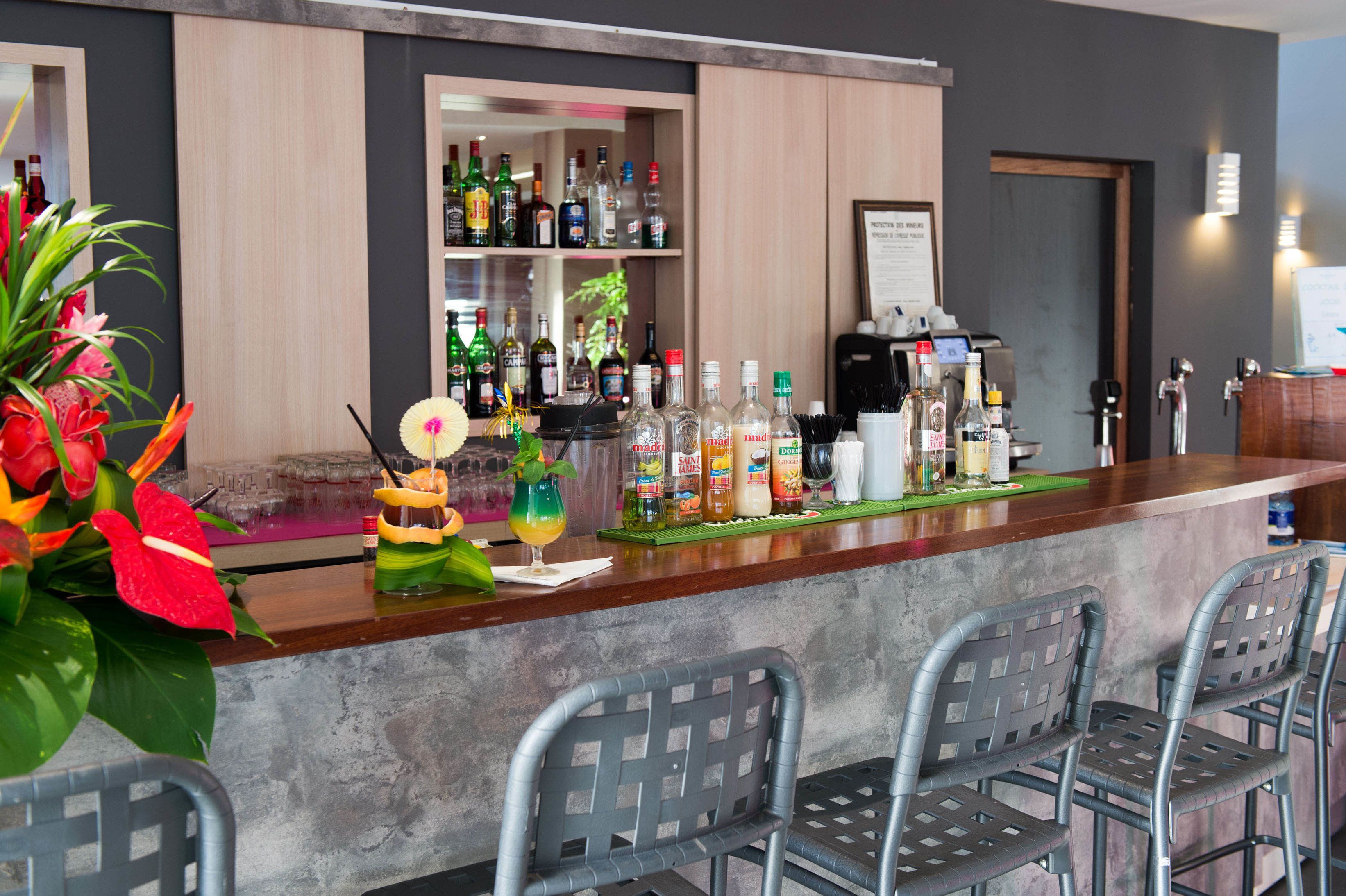 A bar area with a counter, bar stools, and a variety of bottles.