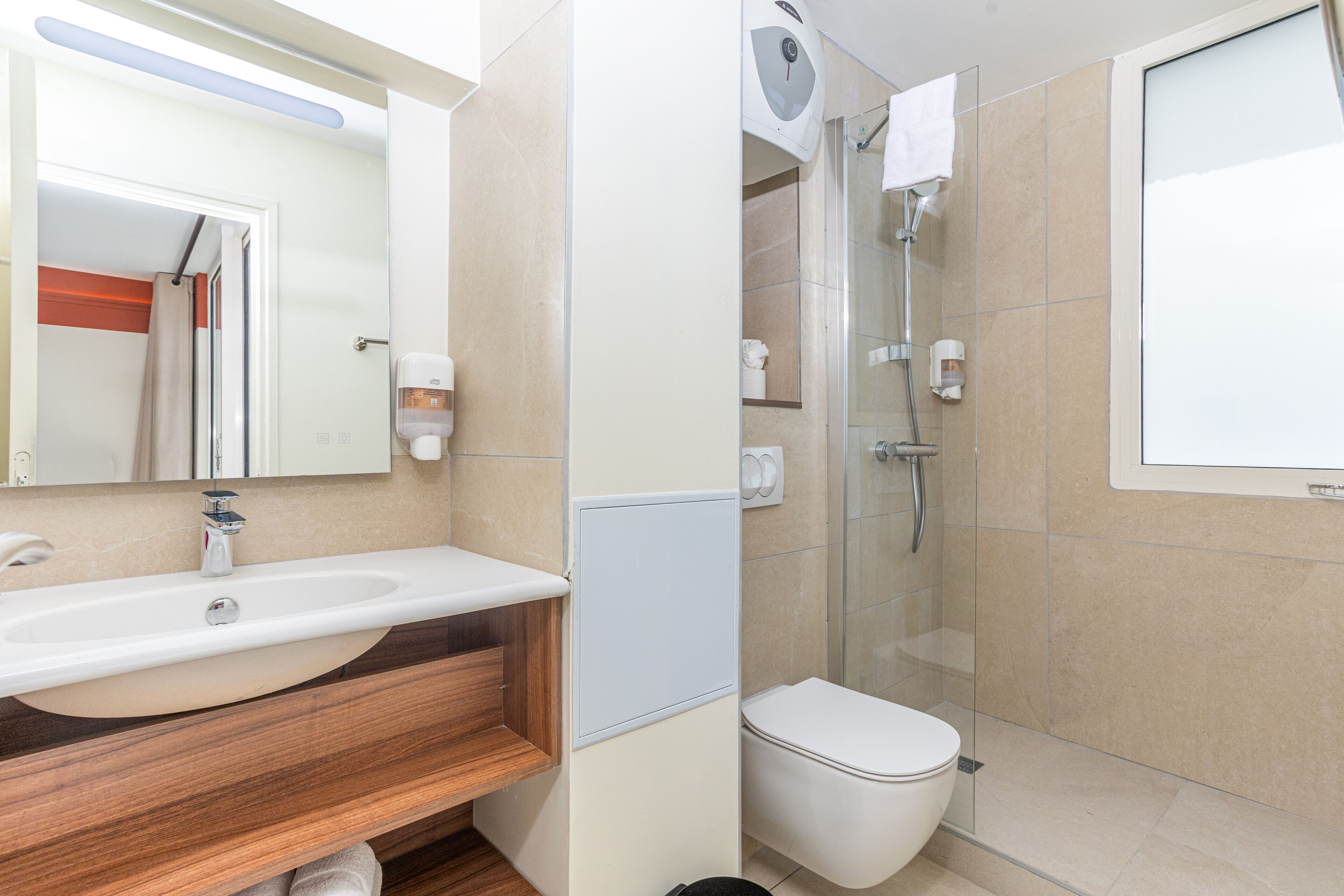 Et moderne badeværelse med vask, spejl, toilet og brusebad.