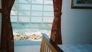 A room with a large window, a wooden bench, and a framed picture on the wall. - Delaporte Point Oceanfront Townhouse (Nassau)