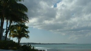 A pool with a view of the ocean and palm trees. - Delaporte Point Oceanfront Townhouse (Nassau)