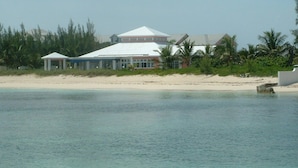 A beachfront property with a large house and a covered area, surrounded by palm trees and a sandy beach. - Delaporte Point Oceanfront Townhouse (Nassau)