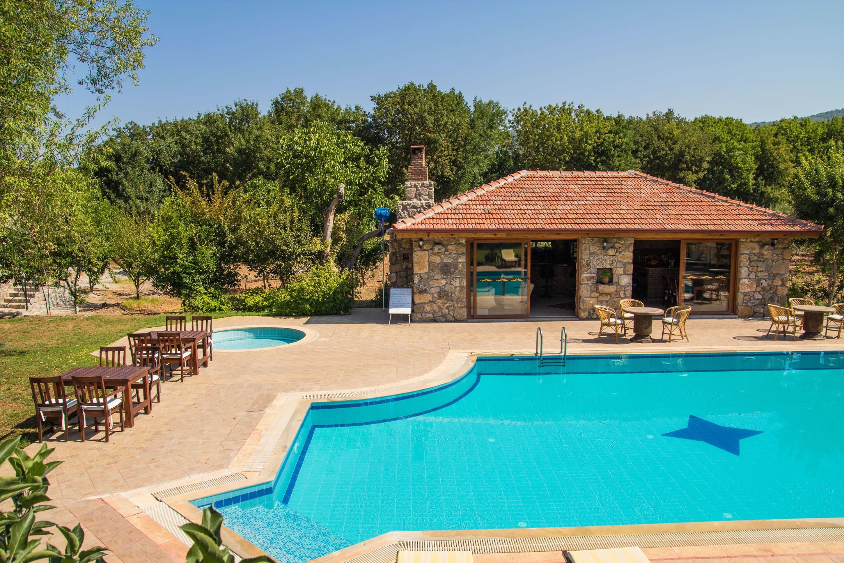 A swimming pool with a stone building and outdoor seating area.