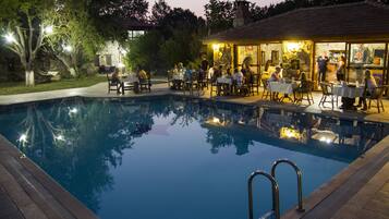 Relax by the pool surrounded by a deck with tables and chairs.
