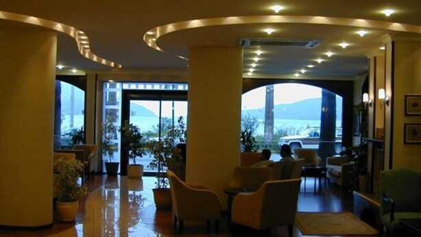 A spacious lobby with a wet floor, large windows offering a view of a mountain and a bridge, and several seating areas. - Candan Beach Hotel (Marmaris)