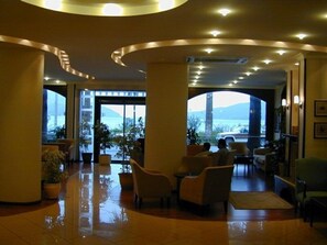 A spacious lobby with a wet floor, large windows offering a view of a mountain and a bridge, and several seating areas. - Candan Beach Hotel (Marmaris)