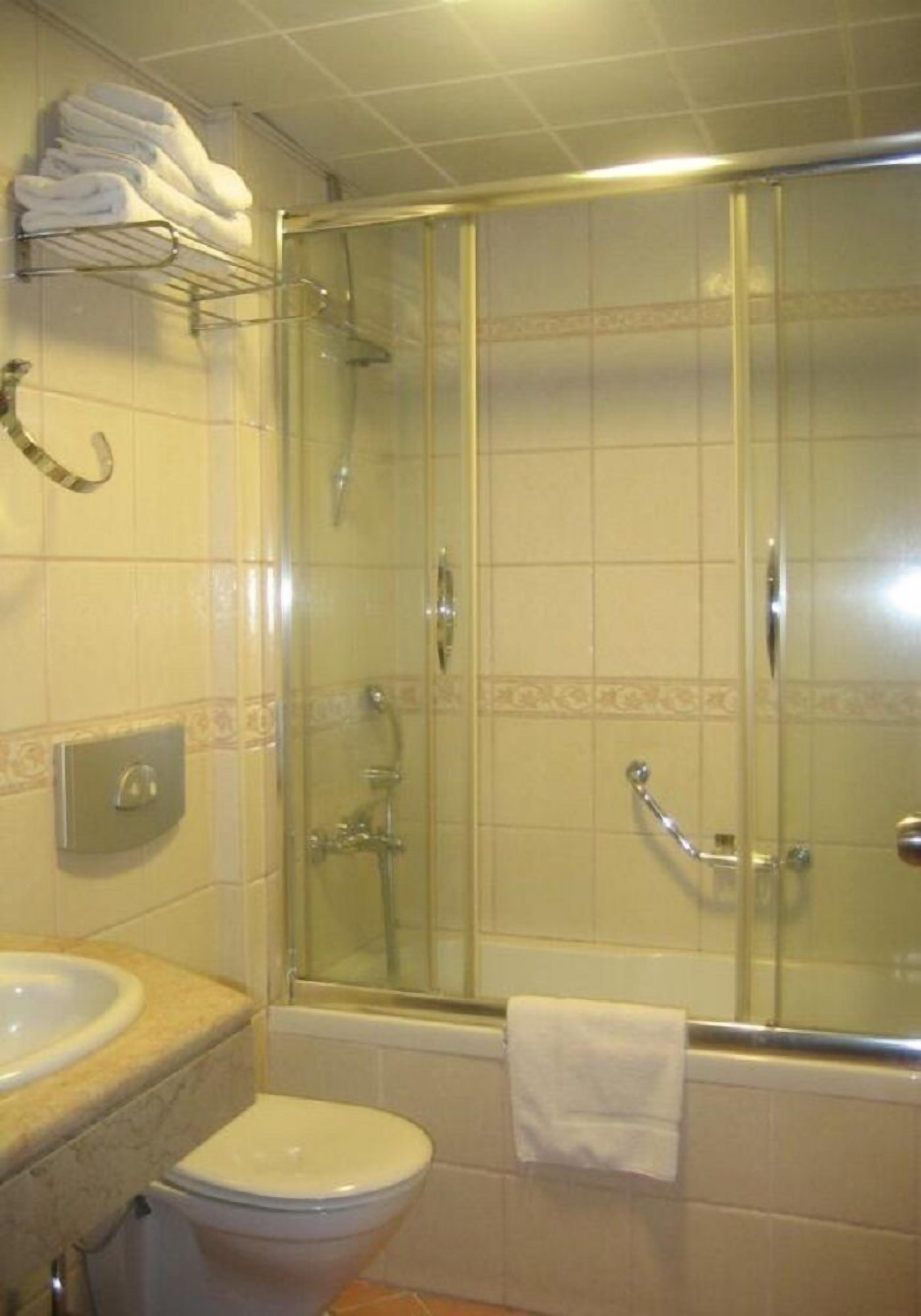 A bathroom with a glass-enclosed shower, a toilet, and a sink.