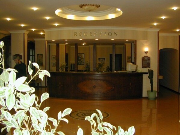 A reception area with a wooden reception desk, a circular ceiling light, and a potted plant. - Candan Beach Hotel (Marmaris)
