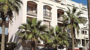 A multi-story building with balconies, palm trees, and storefronts including a restaurant. - Candan Beach Hotel (Marmaris)