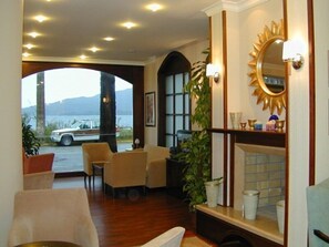 A hotel lobby with a seating area, a large mirror, and a view of the outside. - Candan Beach Hotel (Marmaris)