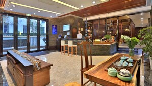 A modern hotel lobby with a reception desk, seating area, and a dining table with teapots. - Hiking Hotel Hangzhou (Hangzhou)