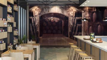 Un restaurante con mesas y sillas de madera, una zona de bar y una pared decorada con barriles.