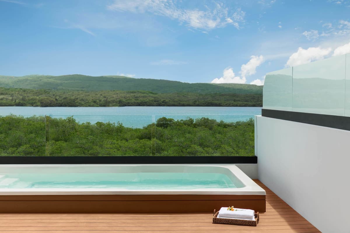 Ein moderner Whirlpool im Freien mit Blick auf einen See und bewaldete Hügel.