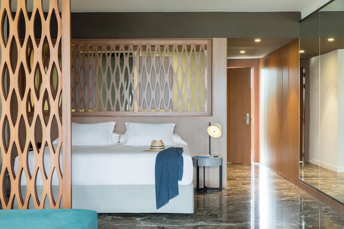 Ein Hotelzimmer mit einem Bett, einem Nachttisch, einer Lampe und einer Holzwand.