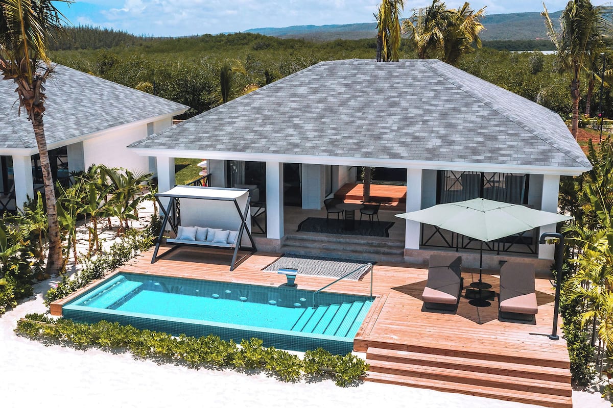 Ein modernes Haus mit Schwimmbad, Außenbereich mit Sitzgelegenheit und Blick auf die umliegende Landschaft.