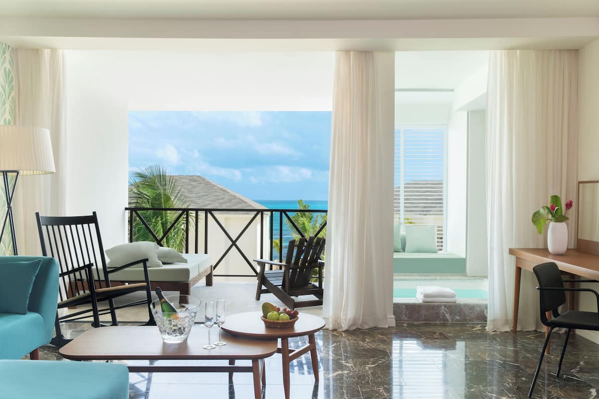 Ein Hotelzimmer mit Balkon, einem Esstisch und Meerblick.